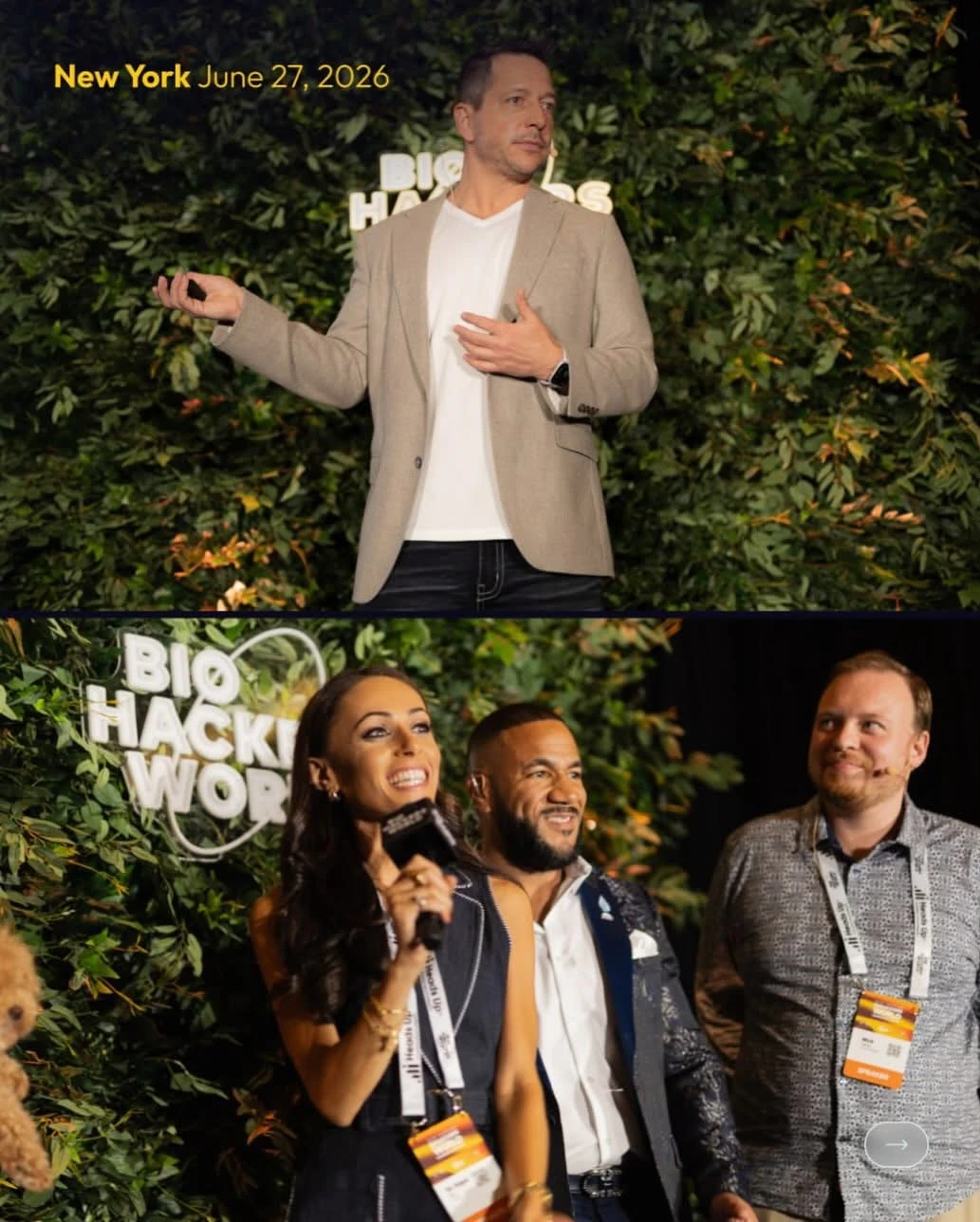 Speaker and panel photographed in front of a greenery wall with illuminated Biohackers World signage at a New York conference