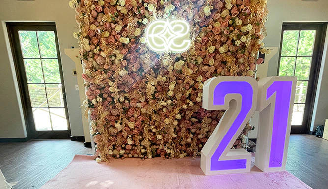 Dusty rose flower wall with a custom monogram neon sign