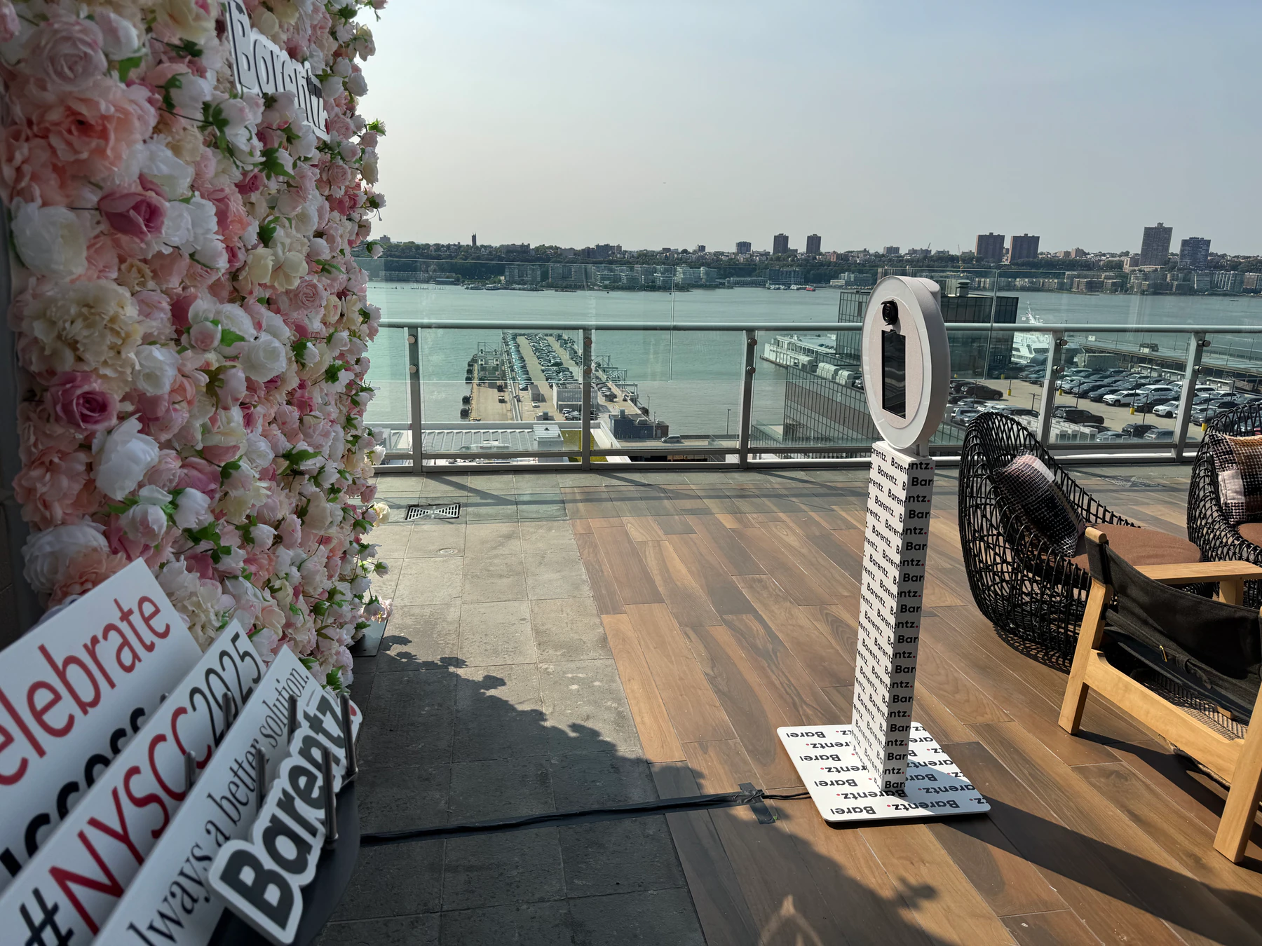 Photo booth positioned beside a blush flower wall with branded signage at a corporate event