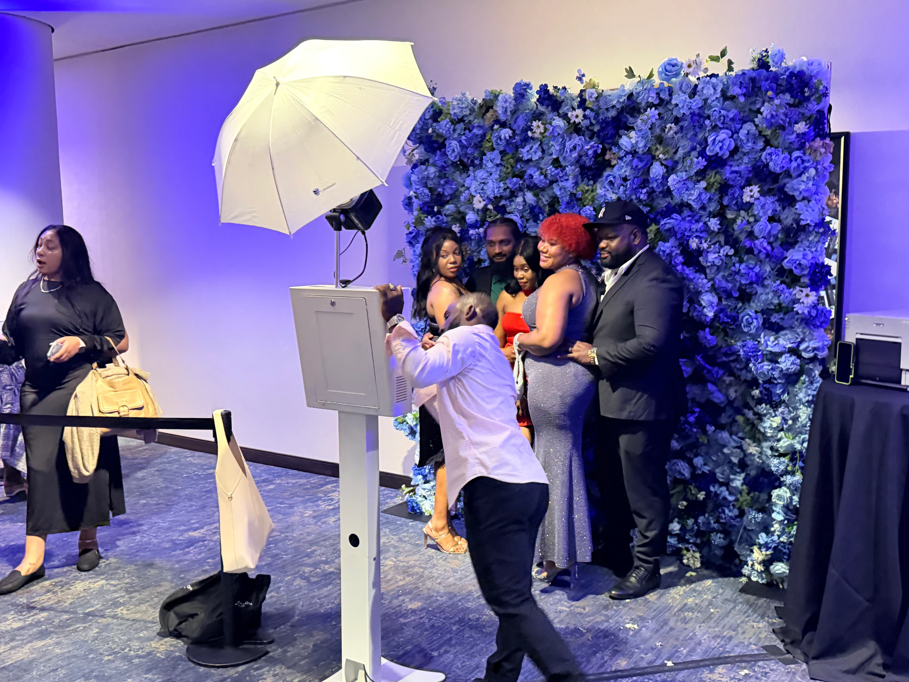 Guests gathered at a photo booth in front of a blue and white flower wall at a New York event