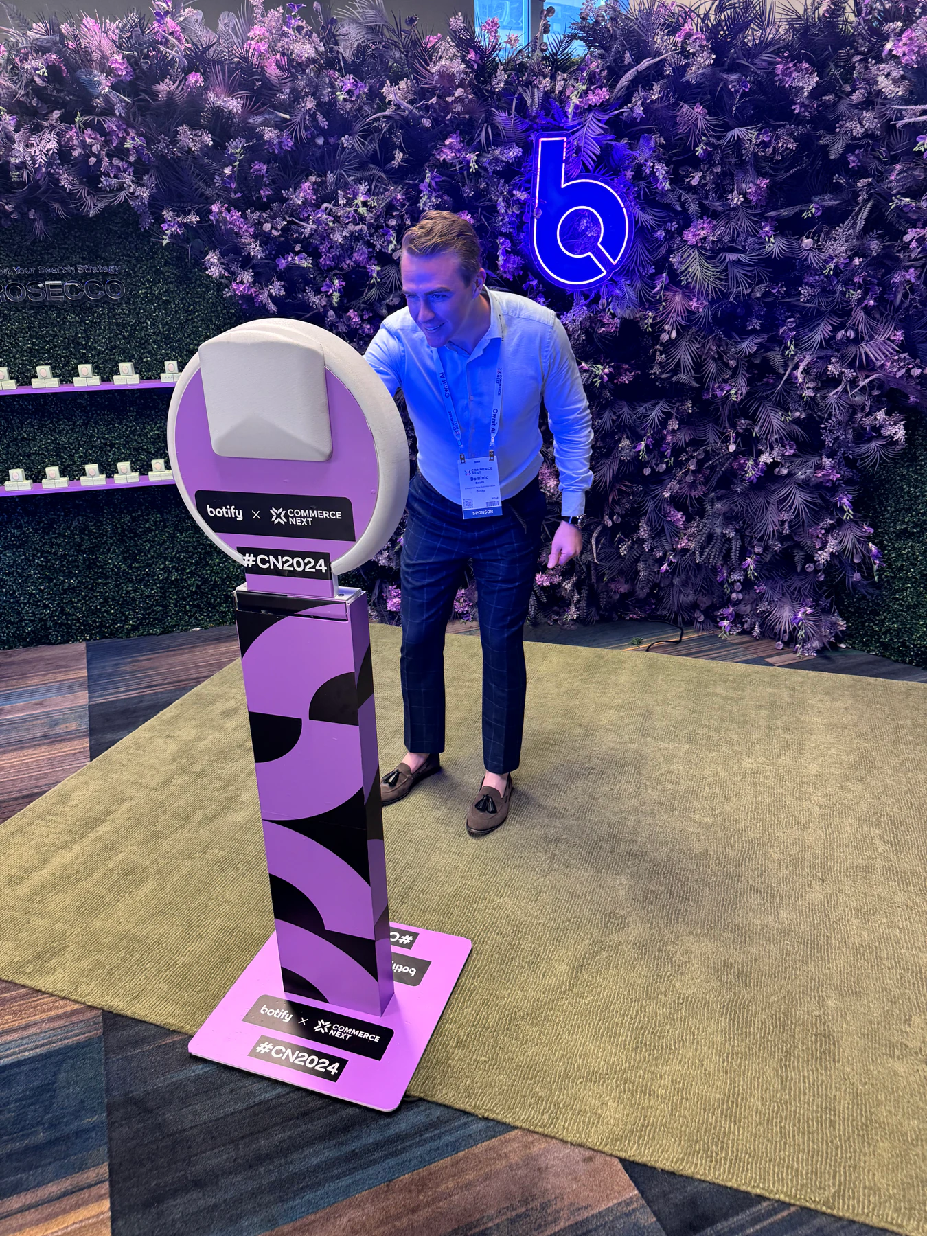 Purple floral wall with a neon logo and a branded photo booth