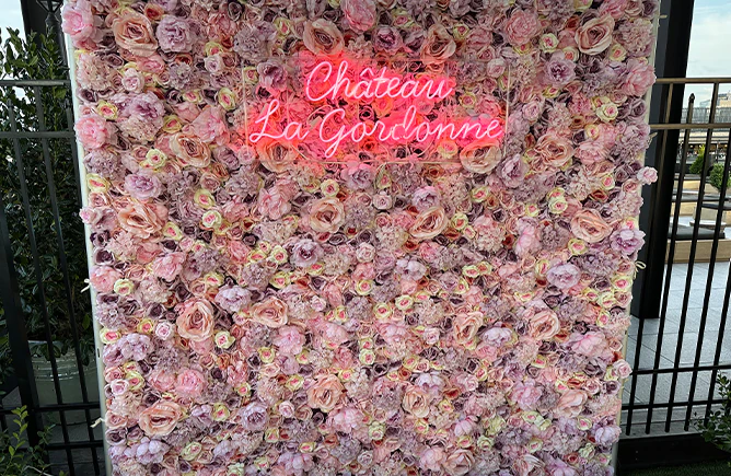 Blush and mauve flower wall with branded neon signage on a rooftop terrace