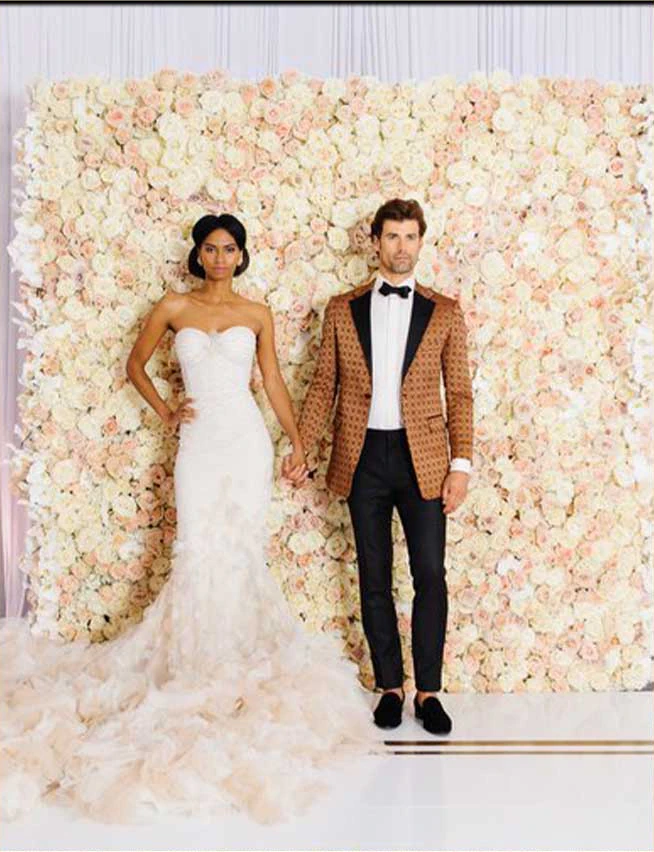 Bride and groom photographed in front of a blush and ivory rose flower wall