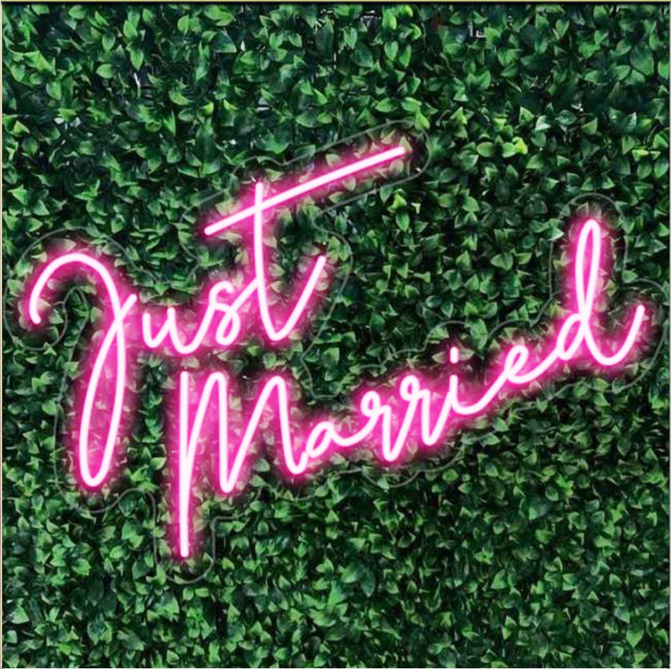 Custom neon signage glowing against a dark floral wall at a New York evening event