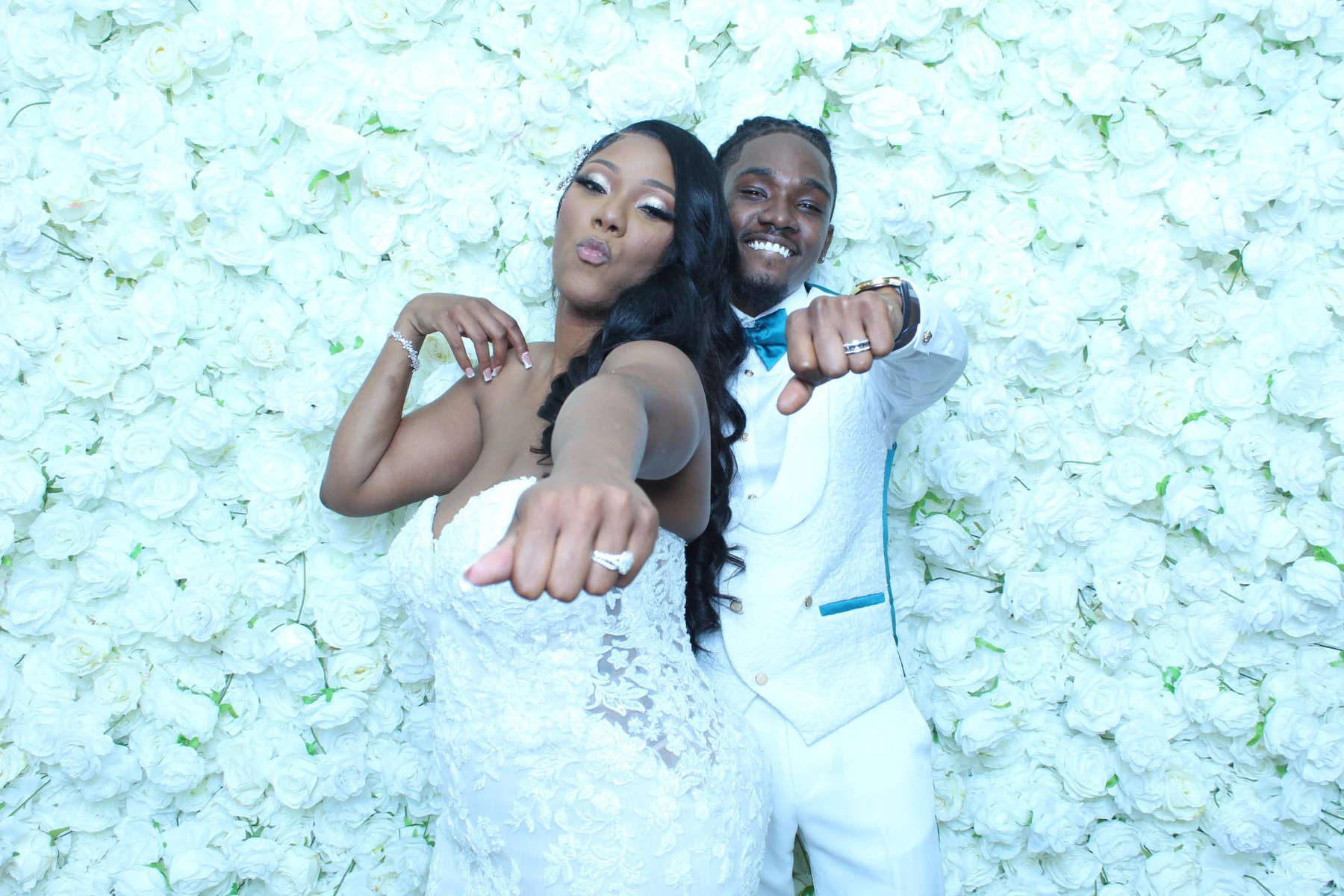 Bride and groom photographed together in front of an all-white rose flower wall at their New York wedding