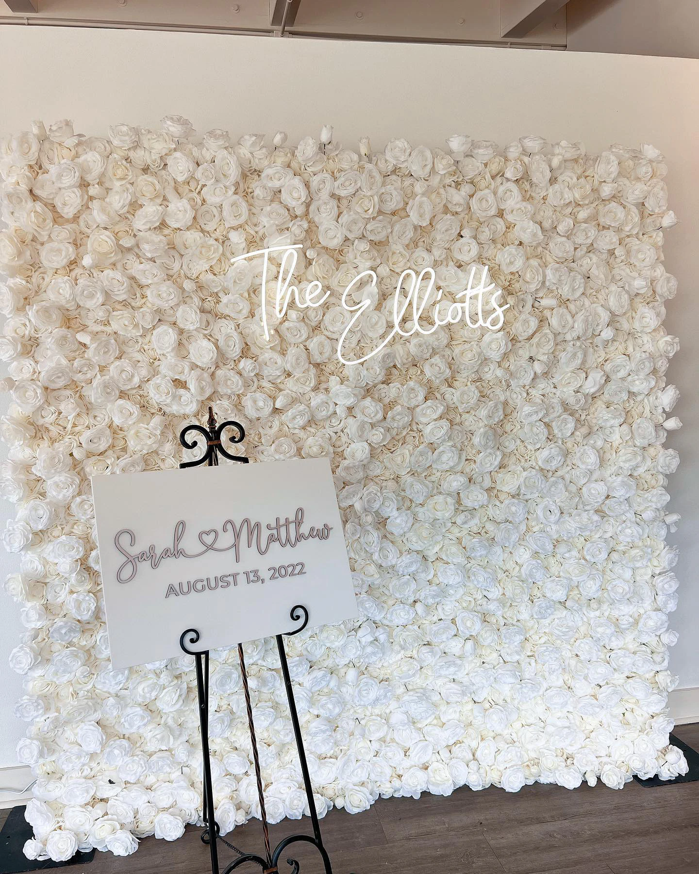 Ivory rose flower wall with custom neon signage at a New York wedding welcome